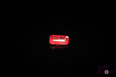 une pilule rouge posée sur une surface noire