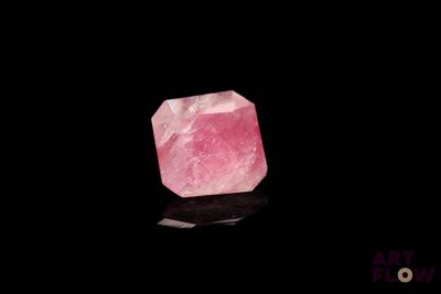 a pink quartz stone on a black surface