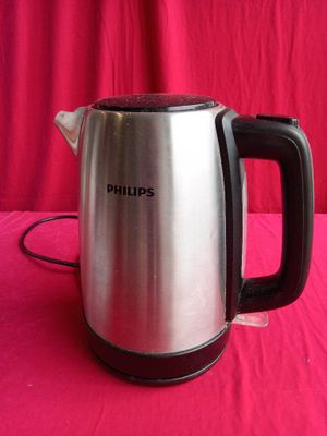 a silver and black electric tea kettle on a pink table