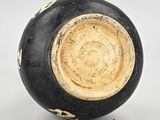 a black and gold vase sitting on a white surface