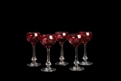 six verres à vin rouge sont alignés sur un fond noir