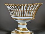 gold and white glass bowl on pedestal on grey background