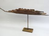 une photo d'une sculpture en bois représentant un bateau, posée sur un socle