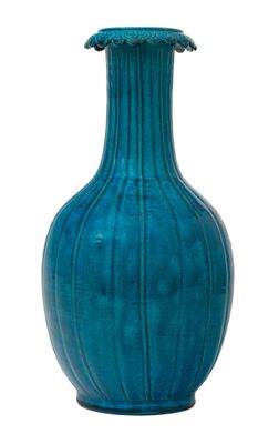 un vase bleu posé sur une surface blanche
