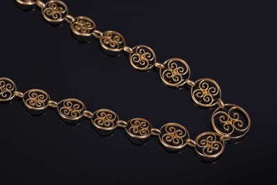 a close up of a gold necklace on a black surface