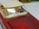 a red toy car with a white top and a steering wheel