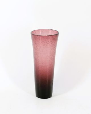 un vase en verre rose posé sur une table blanche