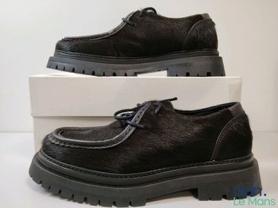 chaussures en cuir noir pour homme, avec semelles en caoutchouc noires, présentées dans une boîte blanche