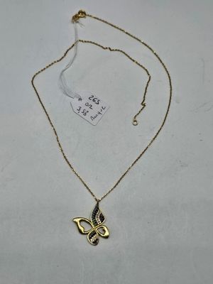 a gold necklace with a black and white butterfly on it