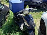 un scooter garé dans l'herbe à côté d'autres voitures