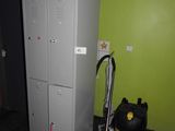 un micro-ondes posé sur un casier, à côté d'un aspirateur