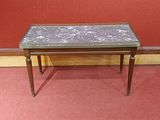 une petite table avec un plateau en carrelage posée sur un tapis rouge
