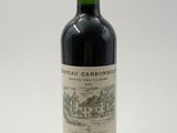 a bottle of red wine sitting on top of a white table