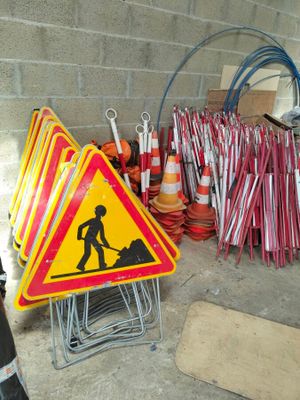 un tas de panneaux de chantier et de cônes posés par terre