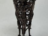 a black vase on a stand on a white surface