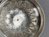 a person holding a silver plate with a flower design on it