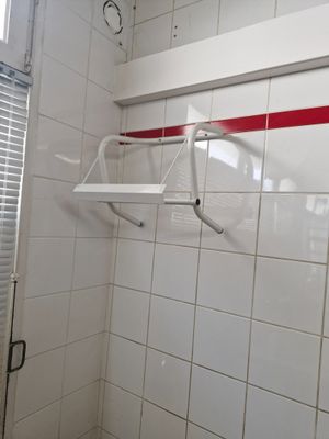 une salle de bains carrelée de blanc avec une bande rouge sur le mur