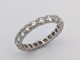 un gros plan d'une bague « éternité » sertie de diamants sur fond blanc