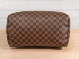 a close up of a brown and black checkered toilet bag on a wooden table