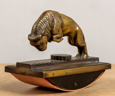 figurine en bronze représentant un taureau, posée sur un socle posé sur une table en bois
