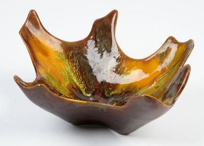 un bol marron et vert posé sur une surface blanche