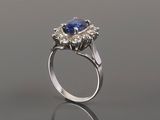 a blue sapphire and diamond ring on a reflective surface