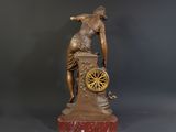 bronze statue of a man leaning over a clock with a wheel on it