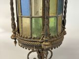 a glass lantern hanging on a metal stand