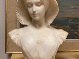 a marble bust of a woman with a bonnet on a table