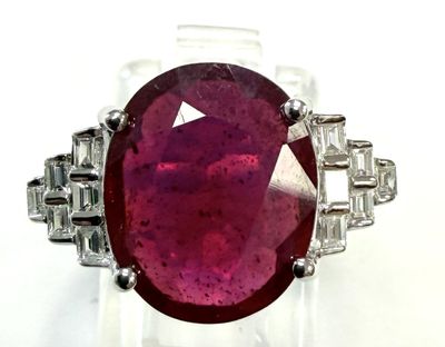 a close up of a ring with a red stone surrounded by diamonds
