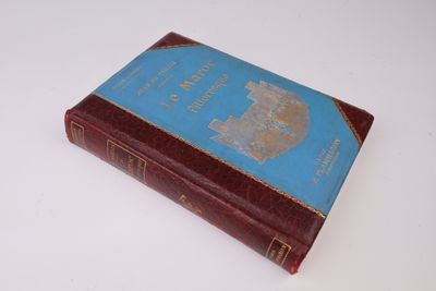 un vieux livre à la couverture bleue posé sur une surface blanche