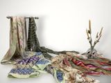 many scarves and a vase with flowers on the table