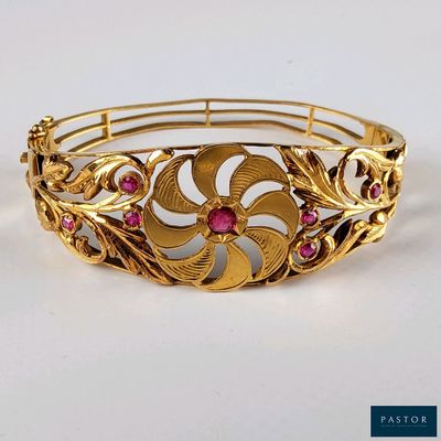 une image représentant un bracelet en or orné de pierres roses sur un fond blanc