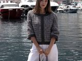 a woman that is standing on a dock with a handbag