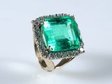 an emerald and diamond ring on a white surface