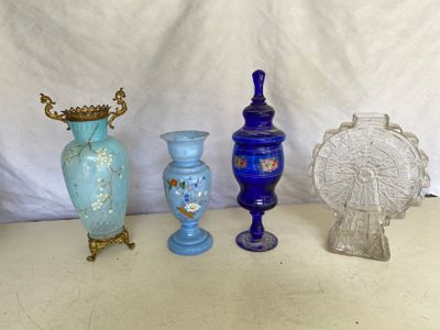 Plusieurs vases en verre sont alignés sur une table devant un fond blanc.