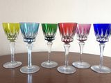 six verres à vin alignés sur une table, avec un mur blanc en arrière-plan