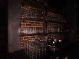 une étagère sur laquelle sont posés des verres à vin, à côté d'un mur en briques
