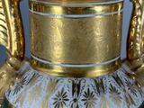 a green and white vase with gold decoration on it