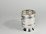 une tasse en argent munie d'une anse, posée sur une table
