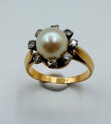 une image d'une bague en perles et diamants sur une surface blanche