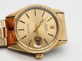 a gold watch with a gold bracelet on a white surface