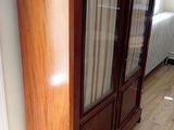 a wooden cabinet with a glass door in a room