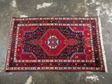 un tapis rouge et noir posé sur un sol en béton