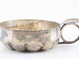 a silver cup with a spoon in it on a white surface