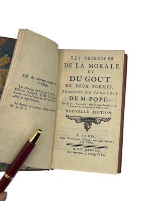 someone is holding a pen and a book open on a white surface