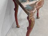 a small wooden table with a painting on top of it