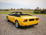 yellow sports car parked in a parking lot next to a grassy field