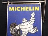 une vieille enseigne « Michel Tire » accrochée à un mur noir