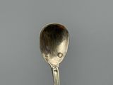a silver spoon with a face on it sitting on a table